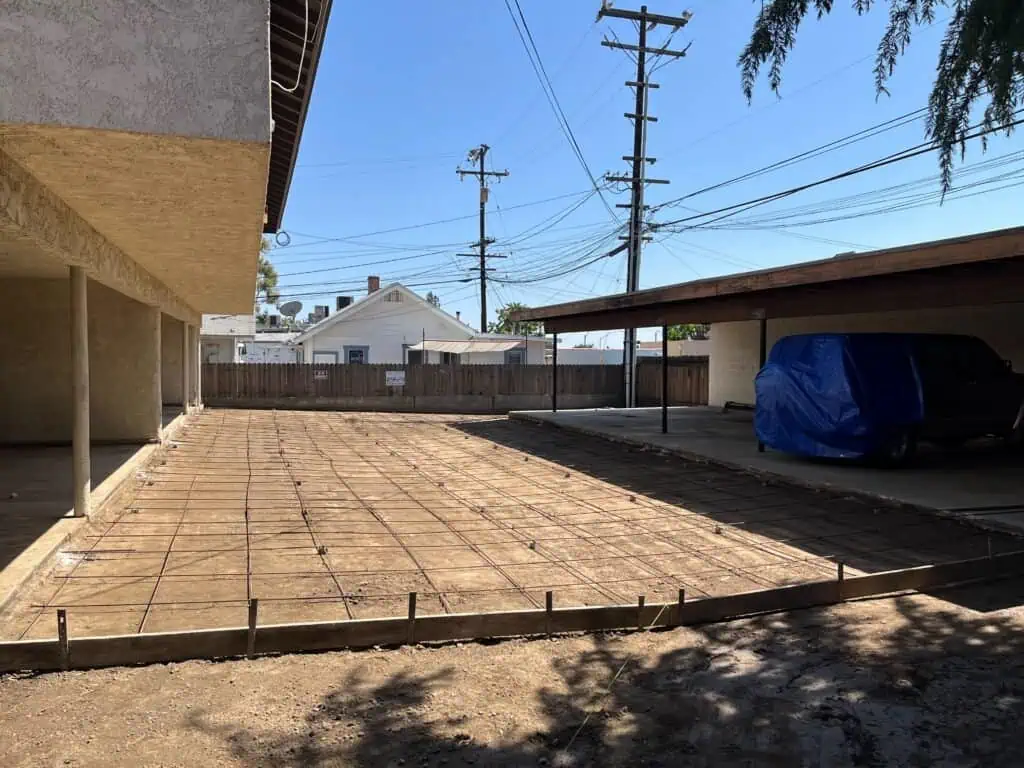Newly poured concrete patio with wooden framing in progress.