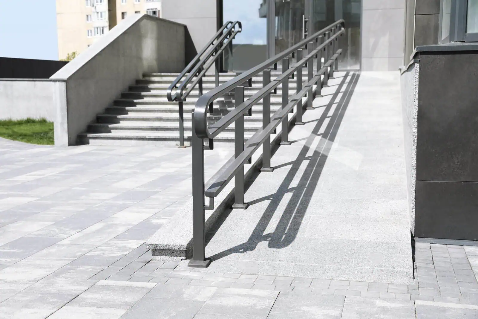 Accessible ramp with handrails outside a modern commercial building.