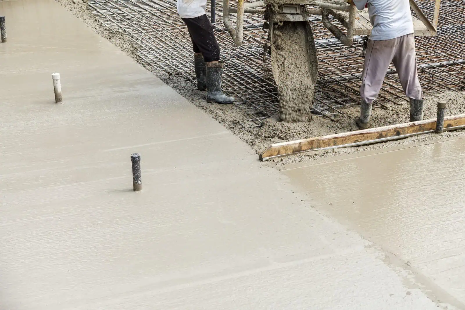 Concrete pouring and finishing by professionals at construction site.